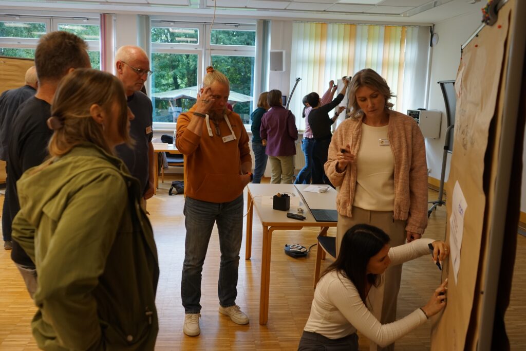 Teilnehmer schreiben beim Workshop der Aktion Mensch an eine Tafel